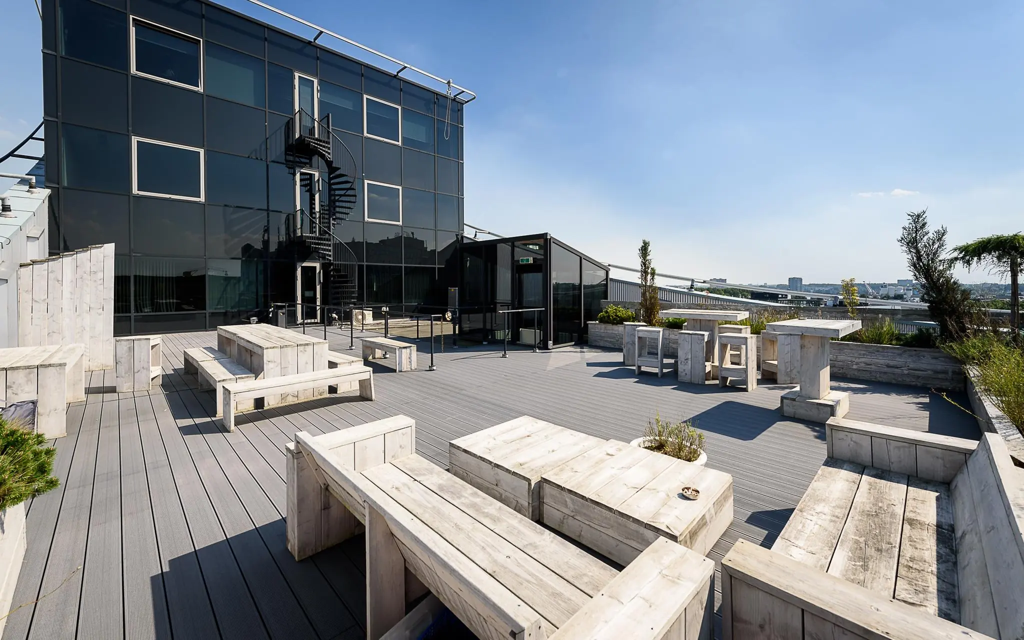 Dakterras met houten zitbanken en tafels bij een modern kantoorpand aan het Rivium Boulevard.